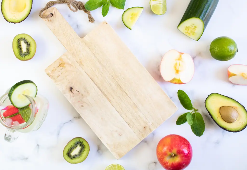 Une planche en bois entourée de fruits et légumes frais